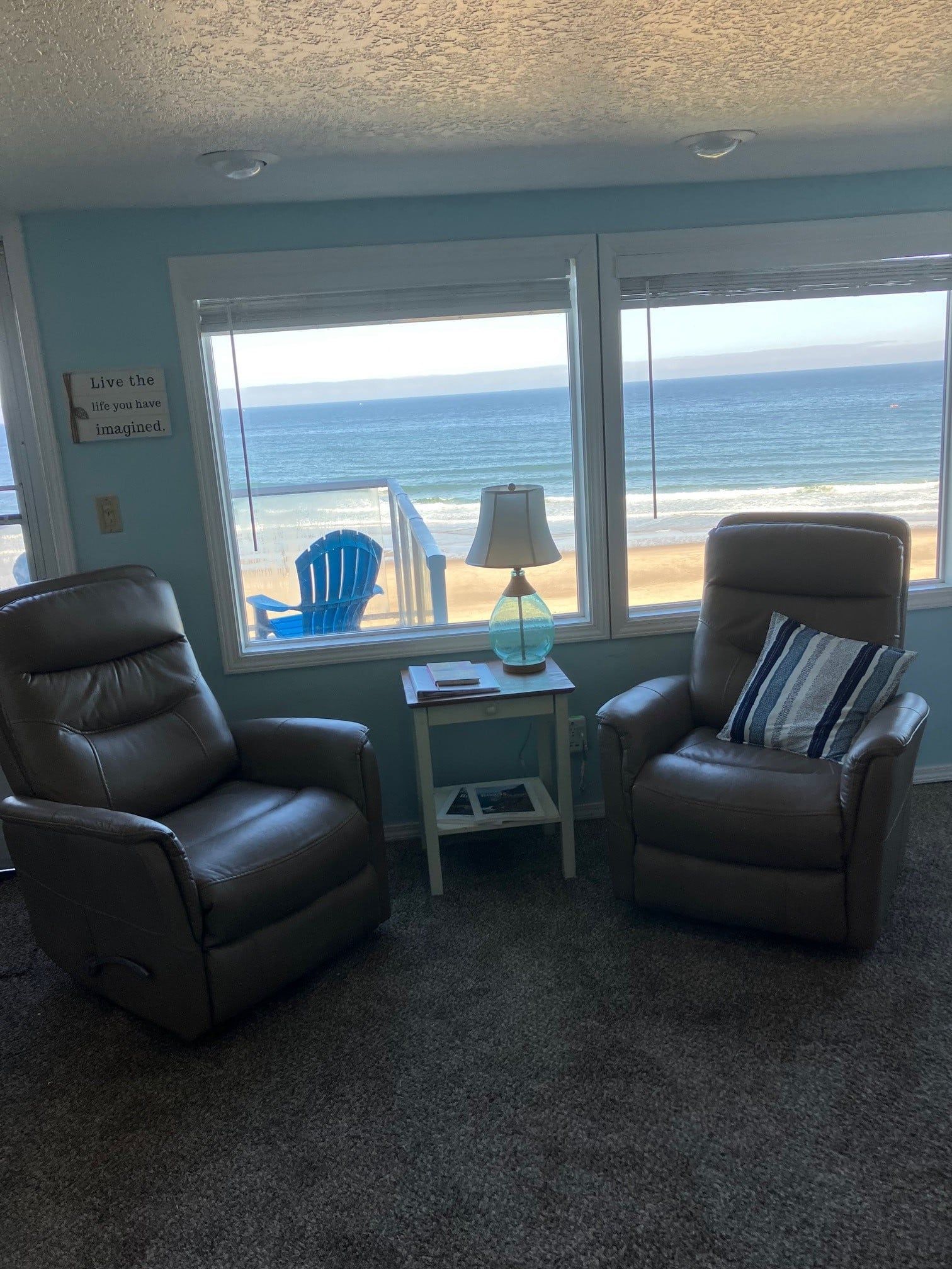 There are two chairs in the living room with a view of the ocean.