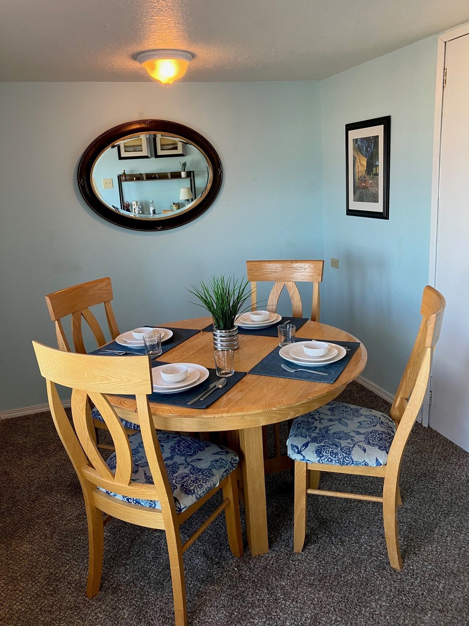 A dining room with a table and chairs and a mirror on the wall.