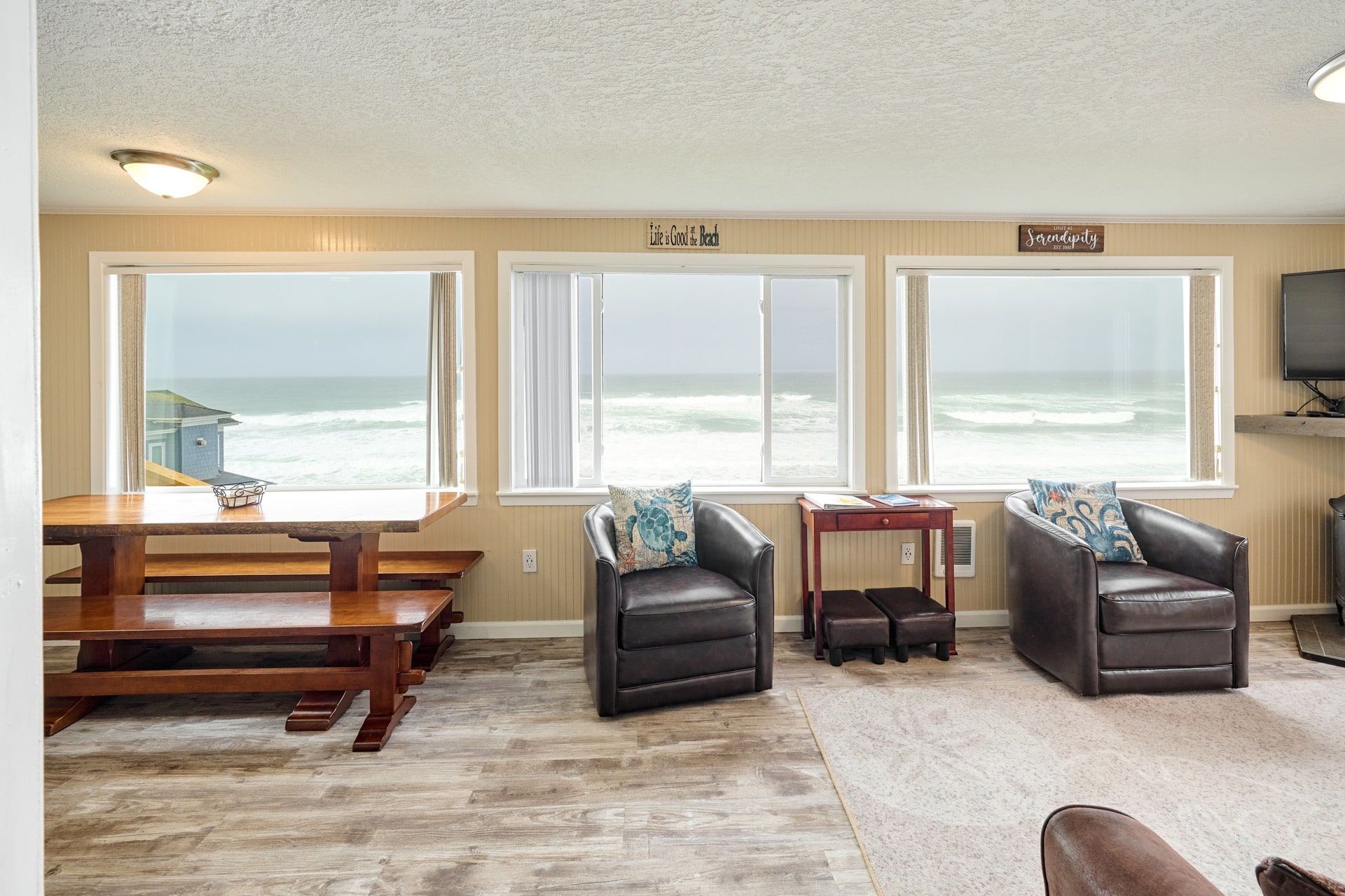 A living room with a table and chairs and a view of the ocean.