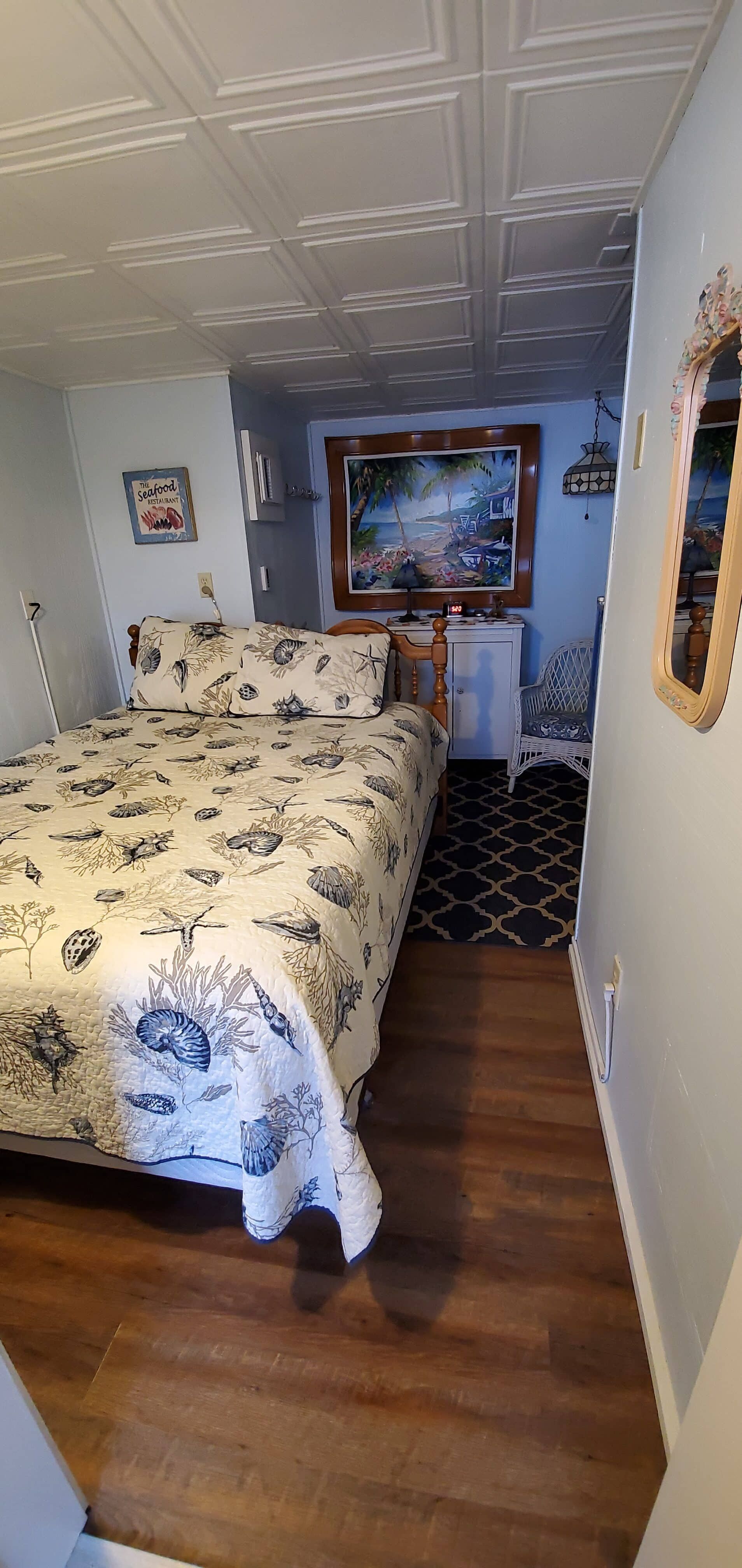 A bedroom with a bed , mirror and painting on the wall.