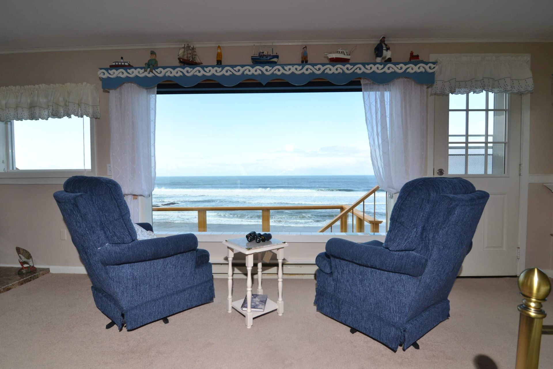 A living room with two blue chairs and a view of the ocean