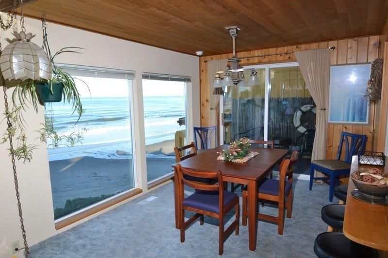 A dining room with a table and chairs and a view of the ocean