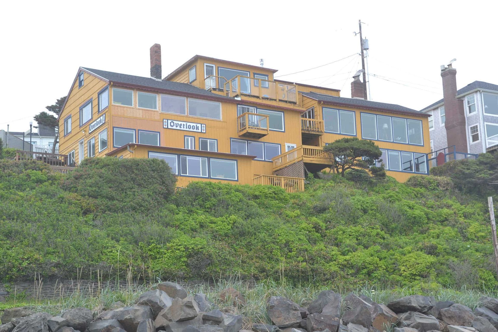 A large yellow house is sitting on top of a hill.