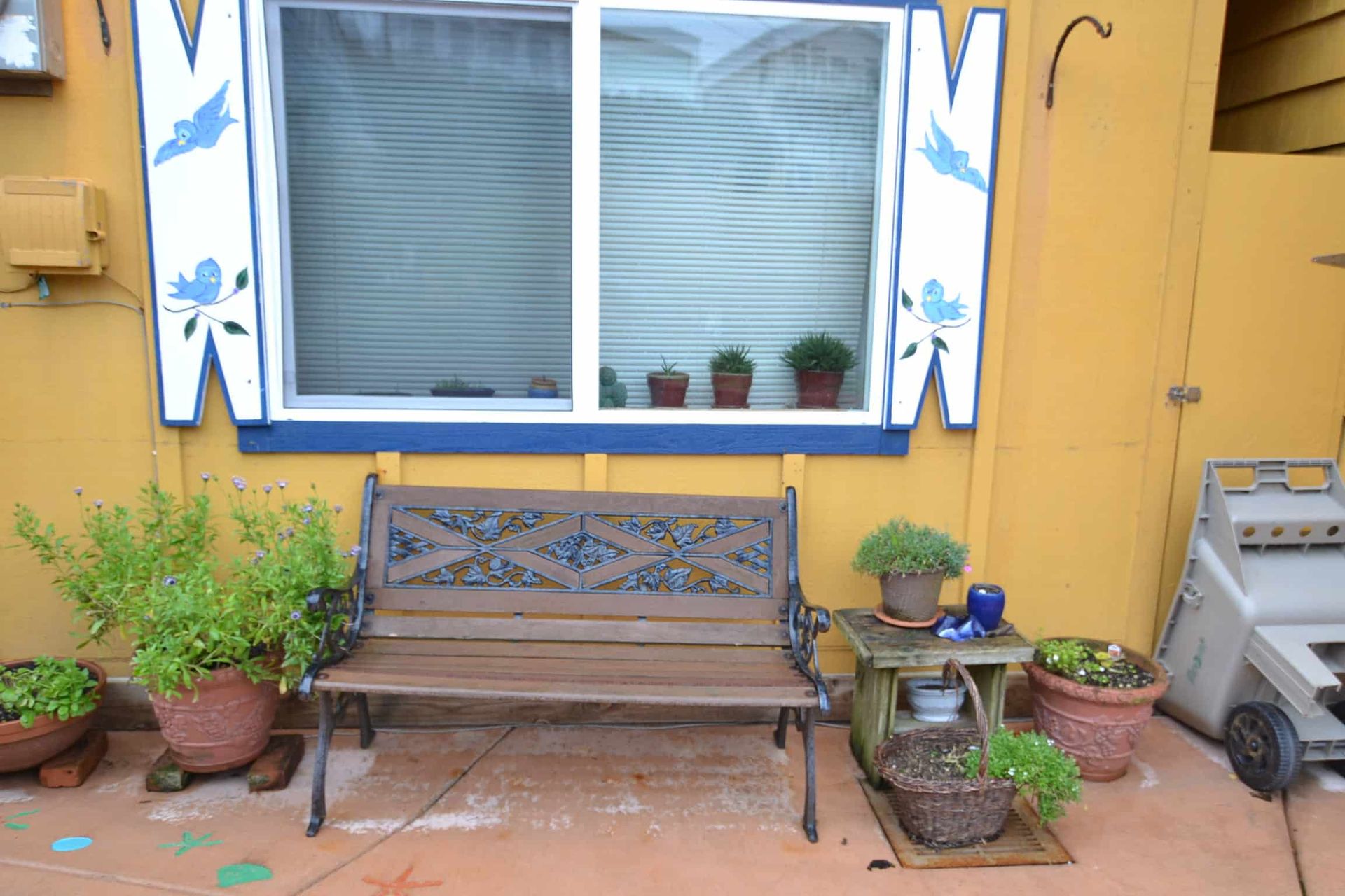 A wooden bench sits in front of a yellow building