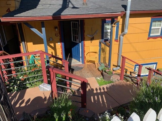 A yellow house with a blue door and a red railing
