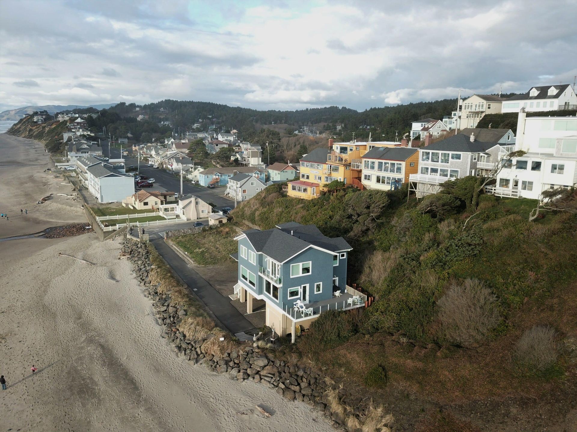An aerial view of a house on a hill next to a beach.
