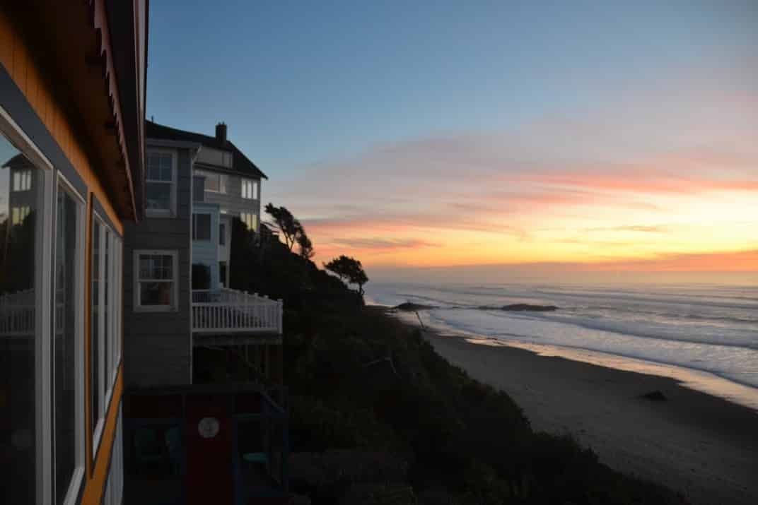 A house on a hill overlooking the ocean at sunset