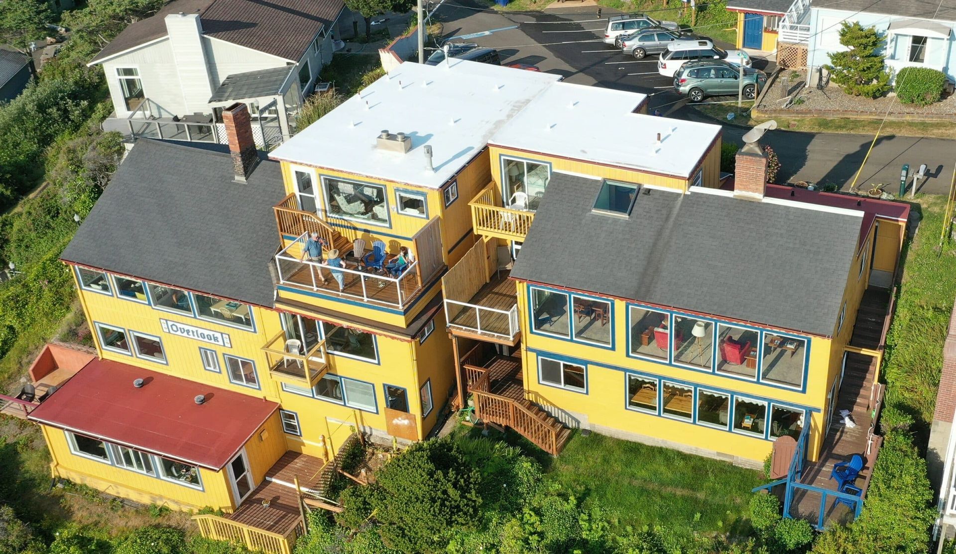 An aerial view of a large yellow house with a white roof