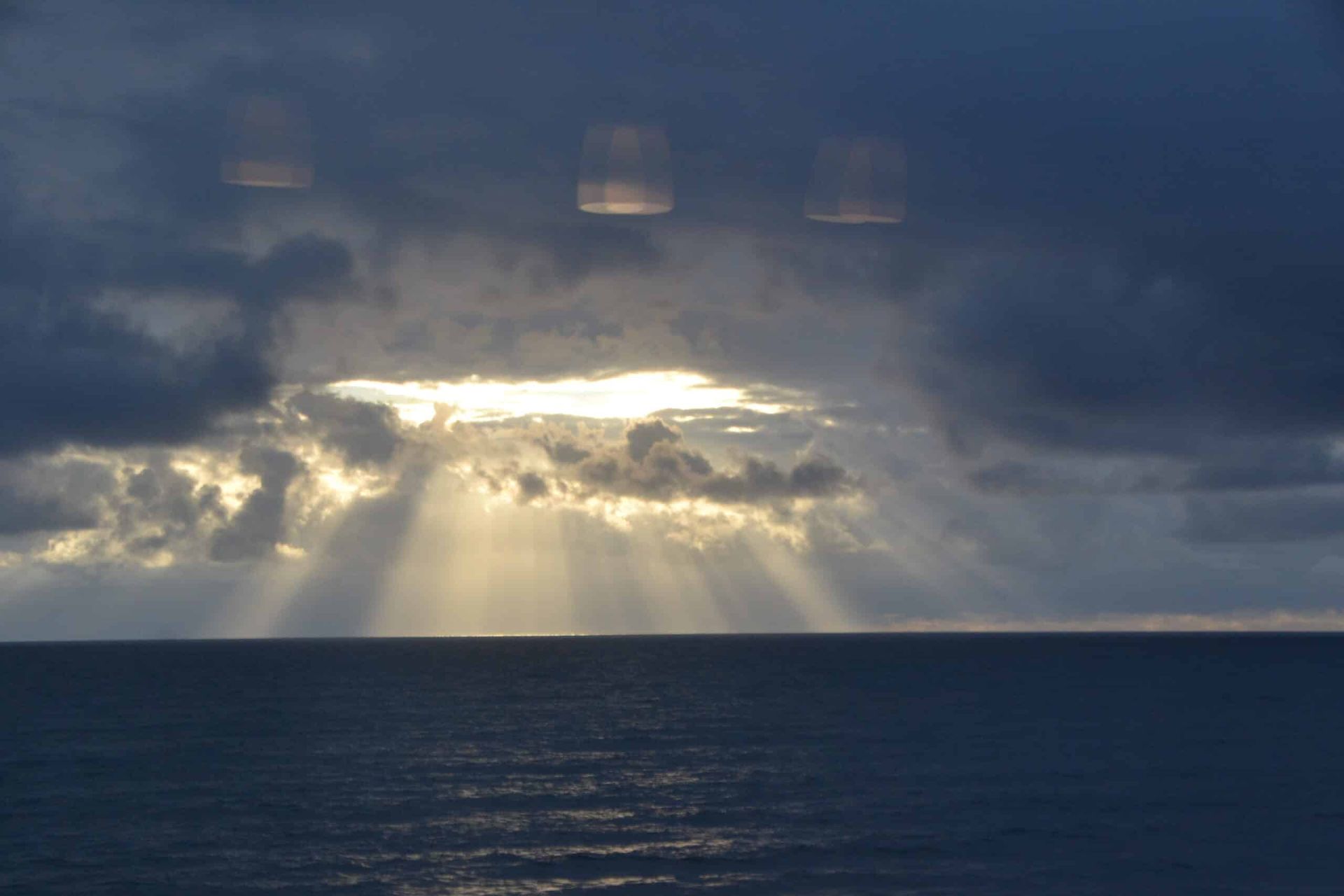 The sun is shining through the clouds over the ocean