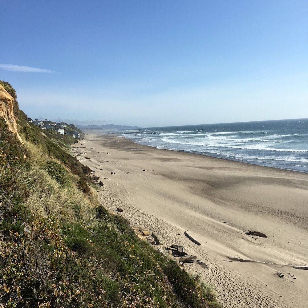 A view of a beach from a cliff on a sunny day