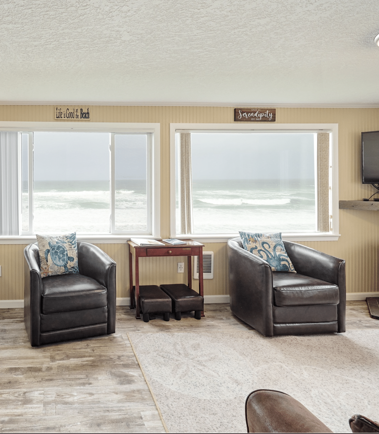 A living room with two chairs and a table with a view of the ocean