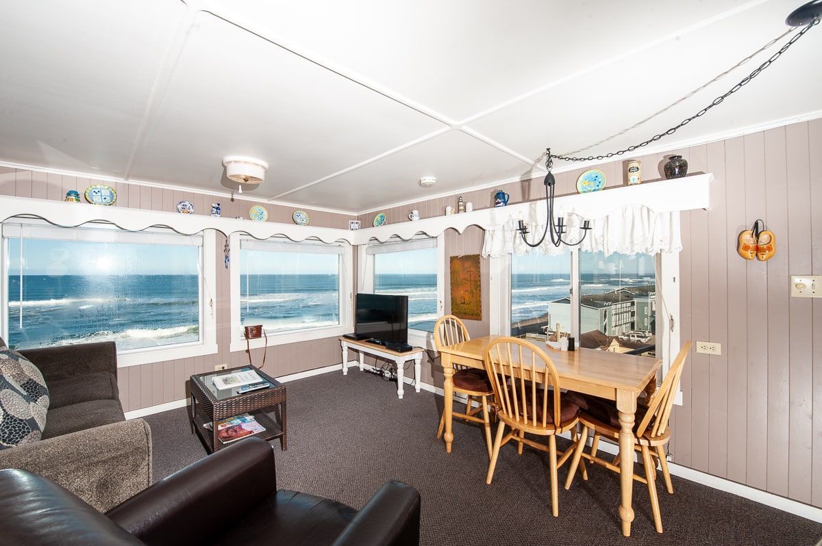 A living room with a table and chairs and a view of the ocean