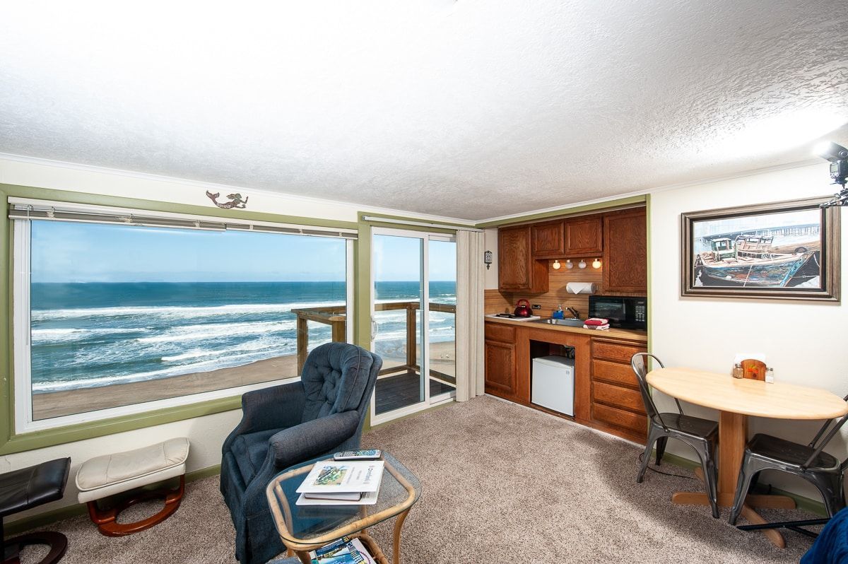 A living room with a table and chairs and a view of the ocean.