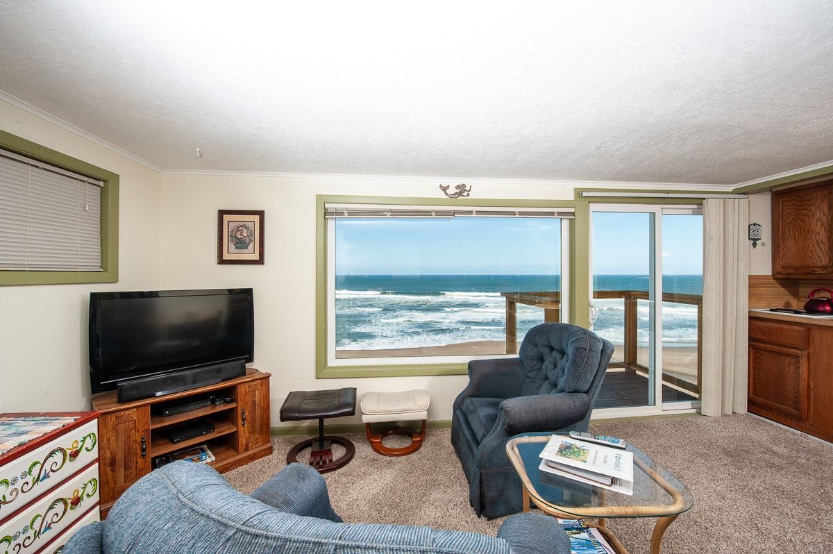A living room with a view of the ocean and a flat screen tv.