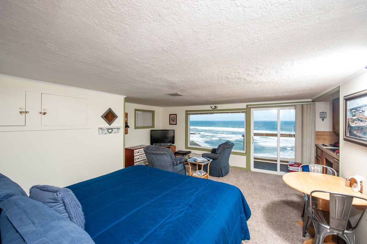 There is a large bed in the middle of the room with a view of the ocean.