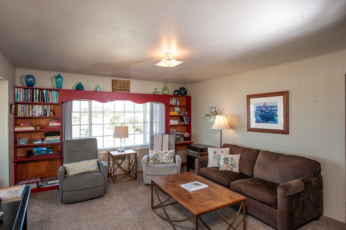 A living room with a couch , chair , coffee table and bookshelf.