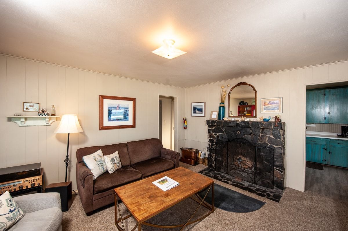 A living room with a couch , chair , coffee table and fireplace.