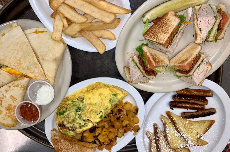 Various breakfast dishes: quesadilla, omelet, sandwiches, fries, toast, and sausage.