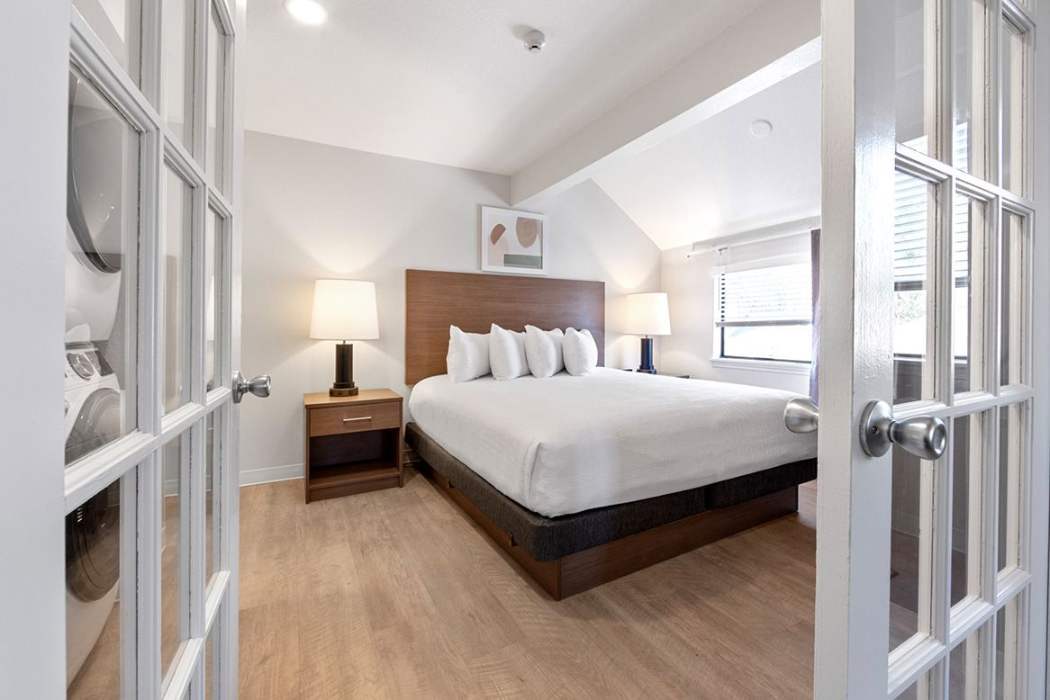 A hotel room with a king size bed and a french door.