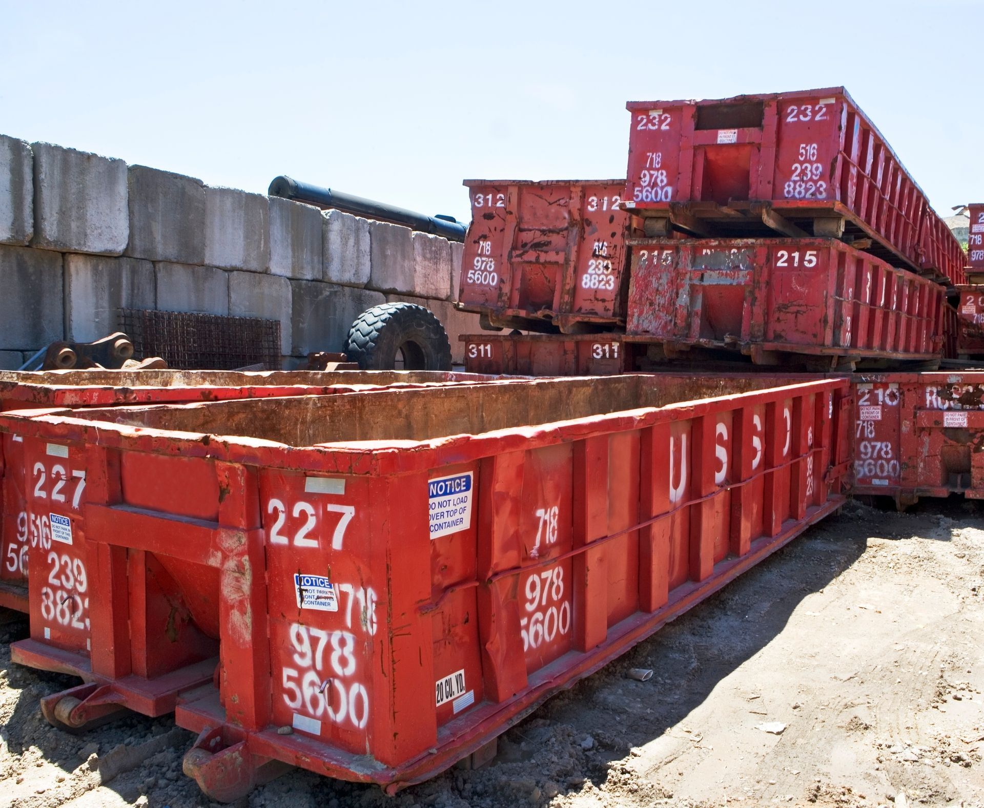 Red metal dumpsters stacked outdoors; the top one is numbered 232.