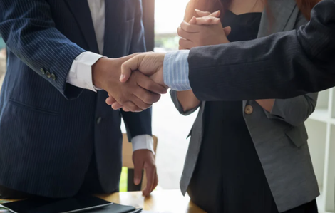 A man and a woman are shaking hands in an office.