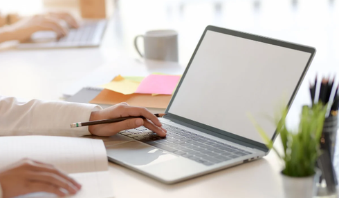 A person is sitting at a desk using a laptop computer.