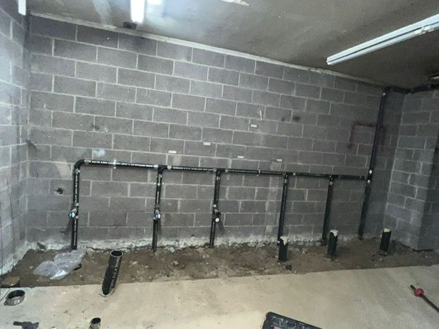 A man is working on a pipe in the dirt.