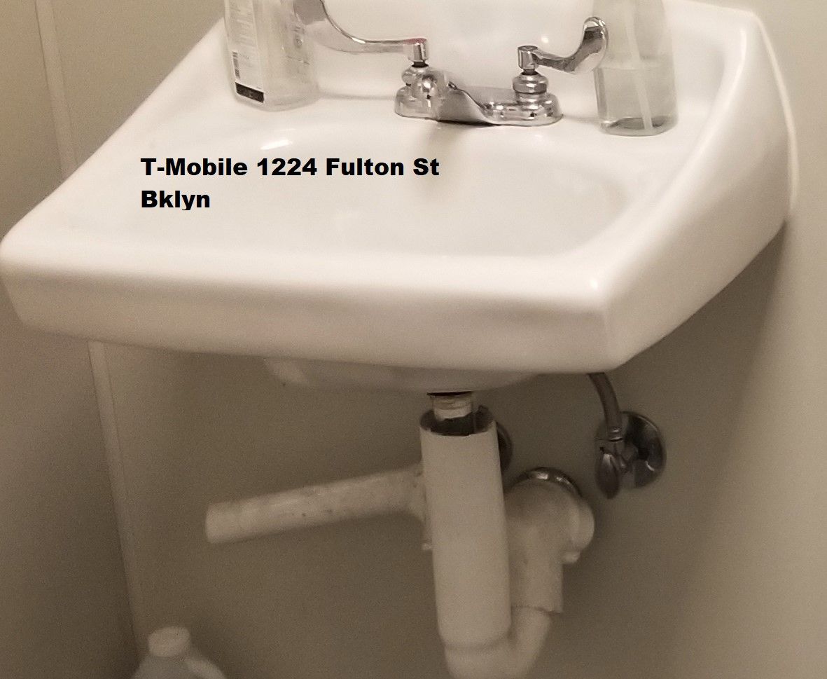 White wall-mounted sink in a T-Mobile store at 1224 Fulton St, Brooklyn. The plumbing beneath the sink is visible.