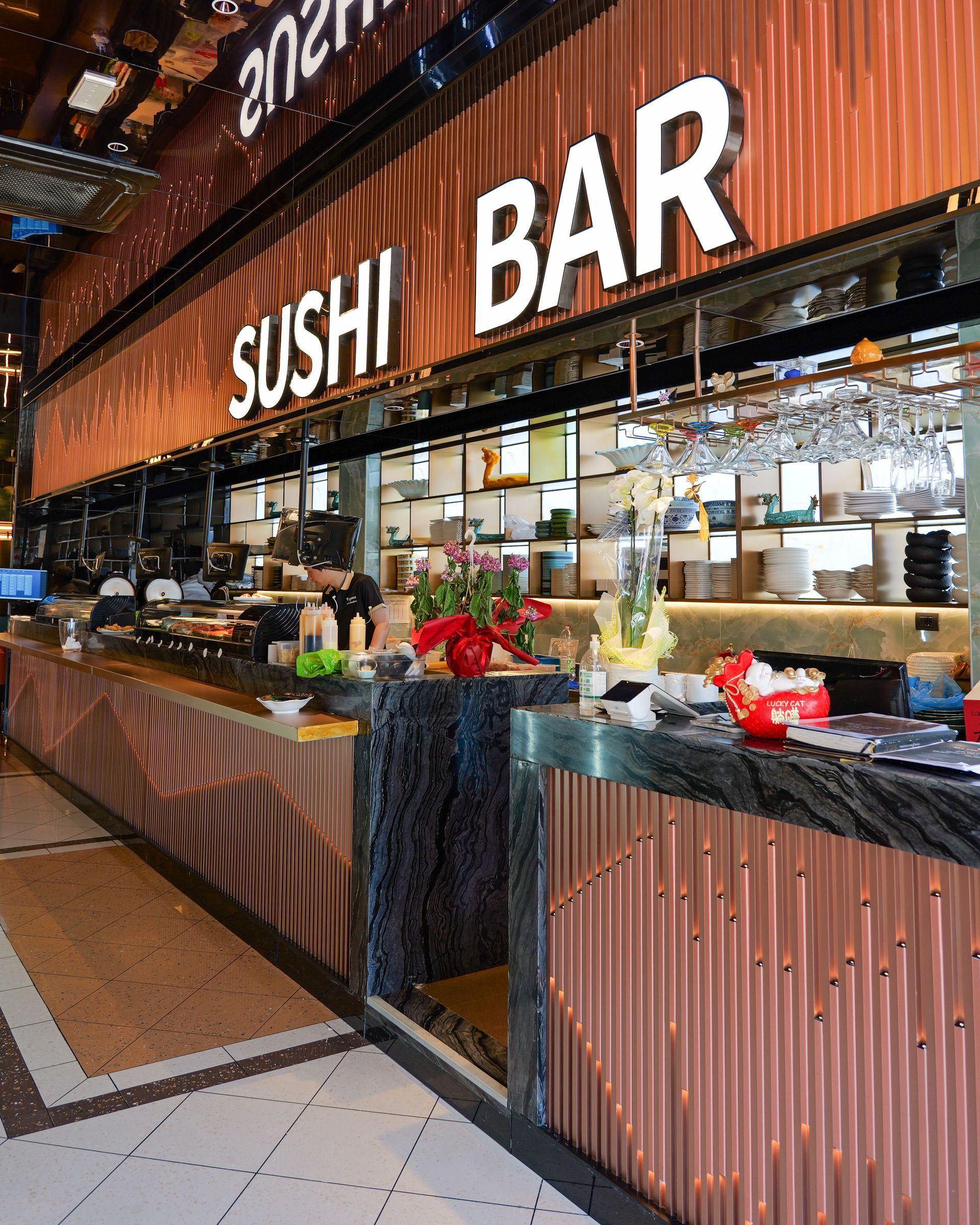 Bancone sushi bar con vetrine e frontale in lamiera ondulata in un mercato della ristorazione.