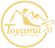 Logo dorato del ristorante Toyama Fusion con montagne stilizzate e bordo circolare.