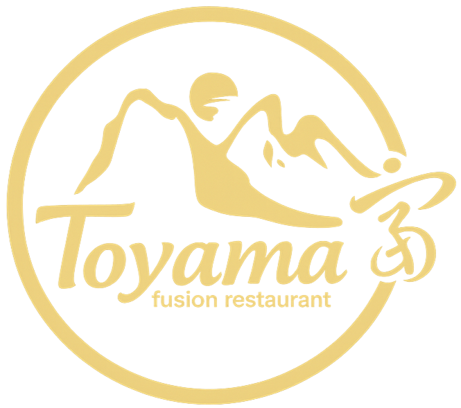 Logo dorato del ristorante Toyama Fusion con montagne stilizzate e bordo circolare.