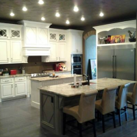 Modern kitchen with white cabinets, dark island, stainless fridge, and gray barstools
