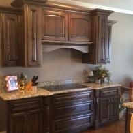 Dark wood kitchen cabinets with granite countertop and decorative items against a beige wall