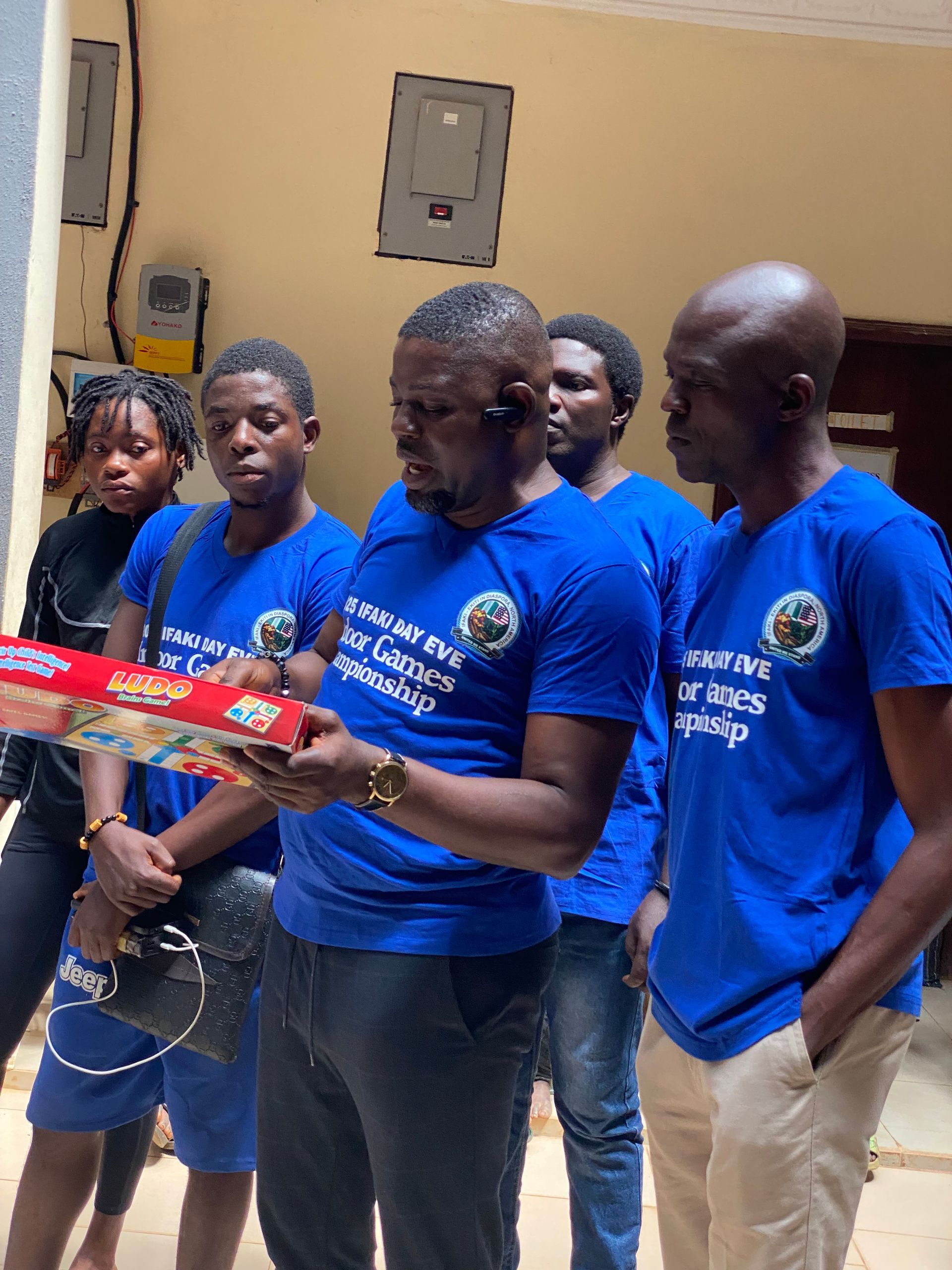 Group of people in blue shirts, holding a package, possibly a donation, in a building.
