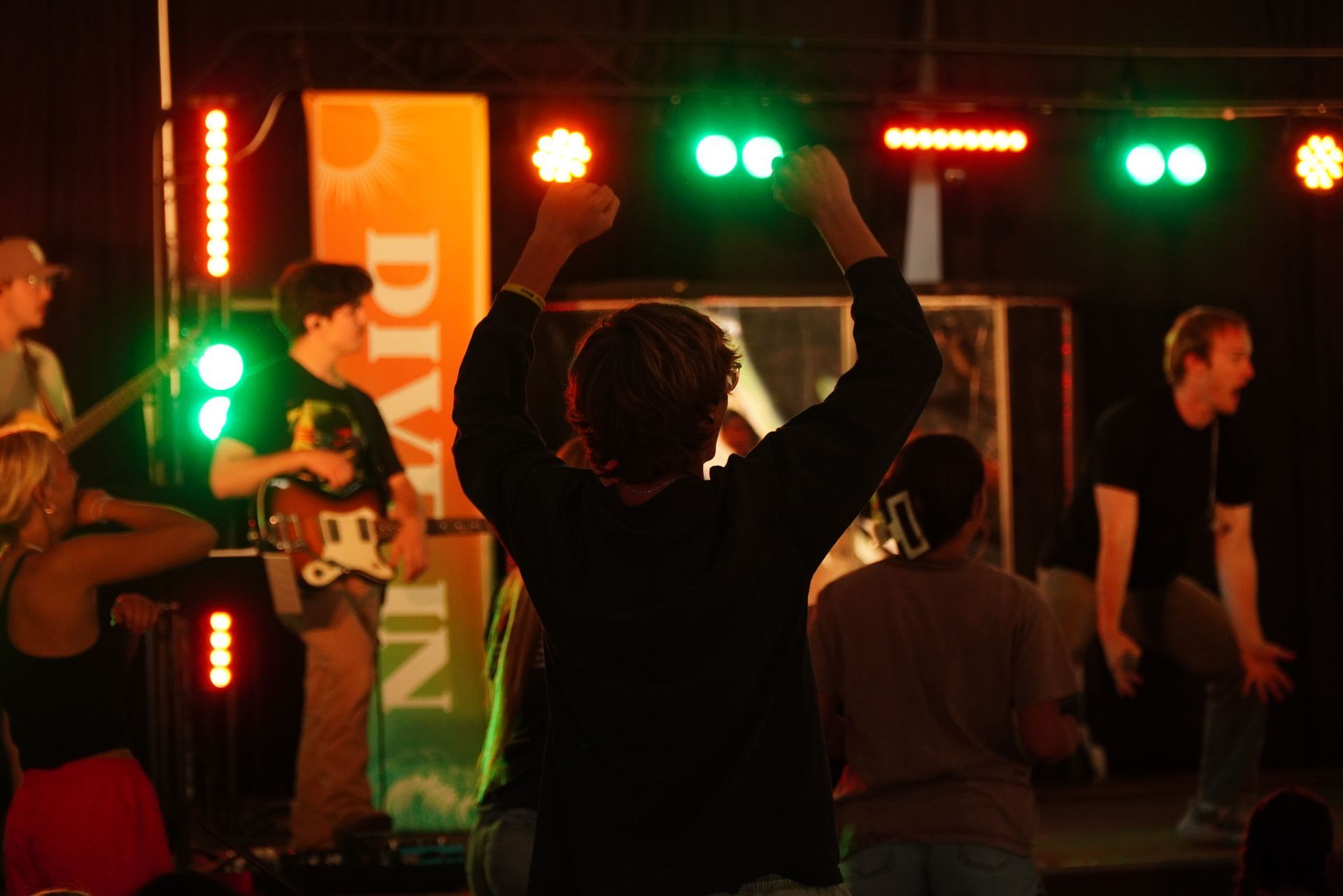 hands raised with lights in background