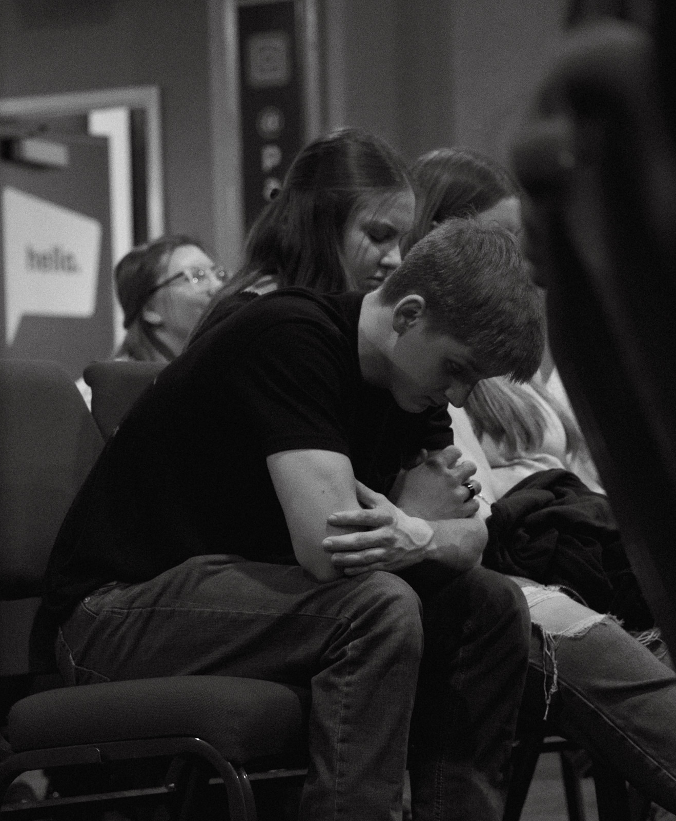 black & white image of young adults, seated and praying