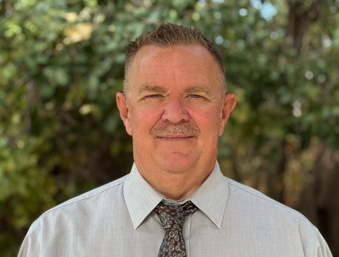 Image of man smiling, standing in front of plants