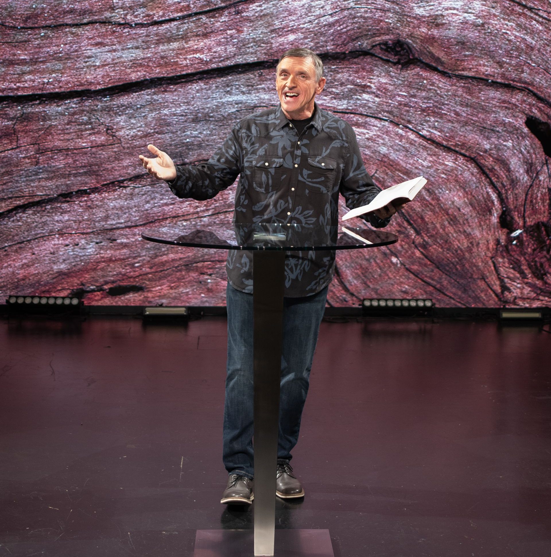 pastor standing on a stage, holding a Bible and talking