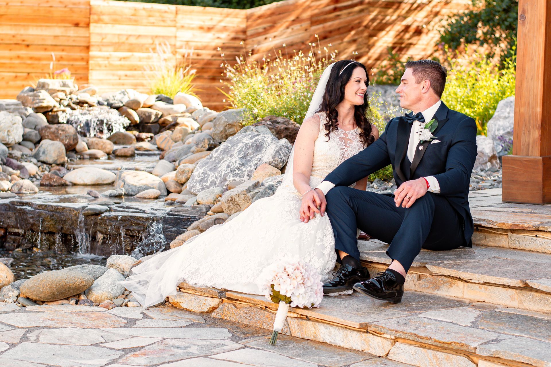 bride and groom sitting by water feature