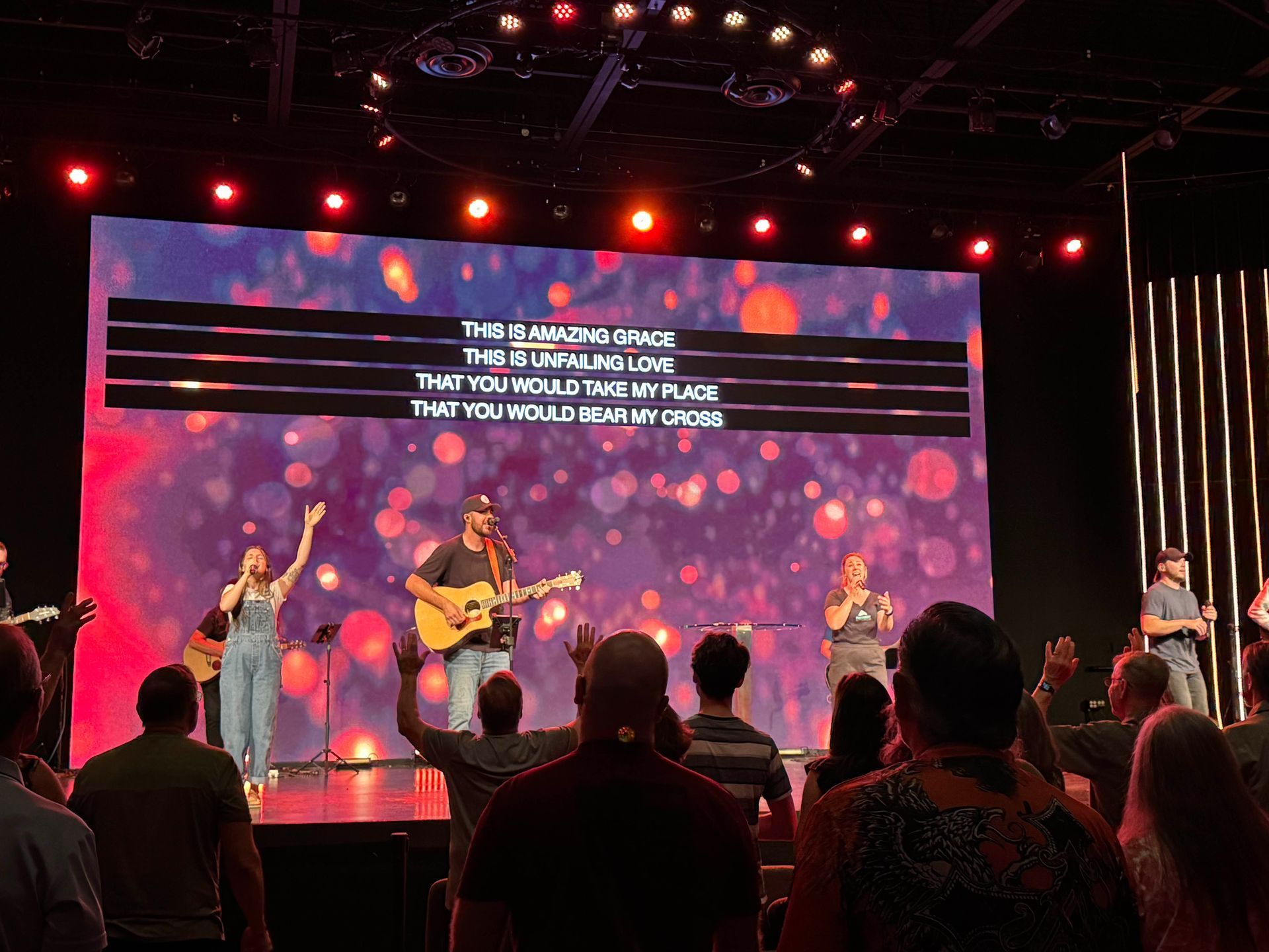 image of people on stage, singing and playing instruments