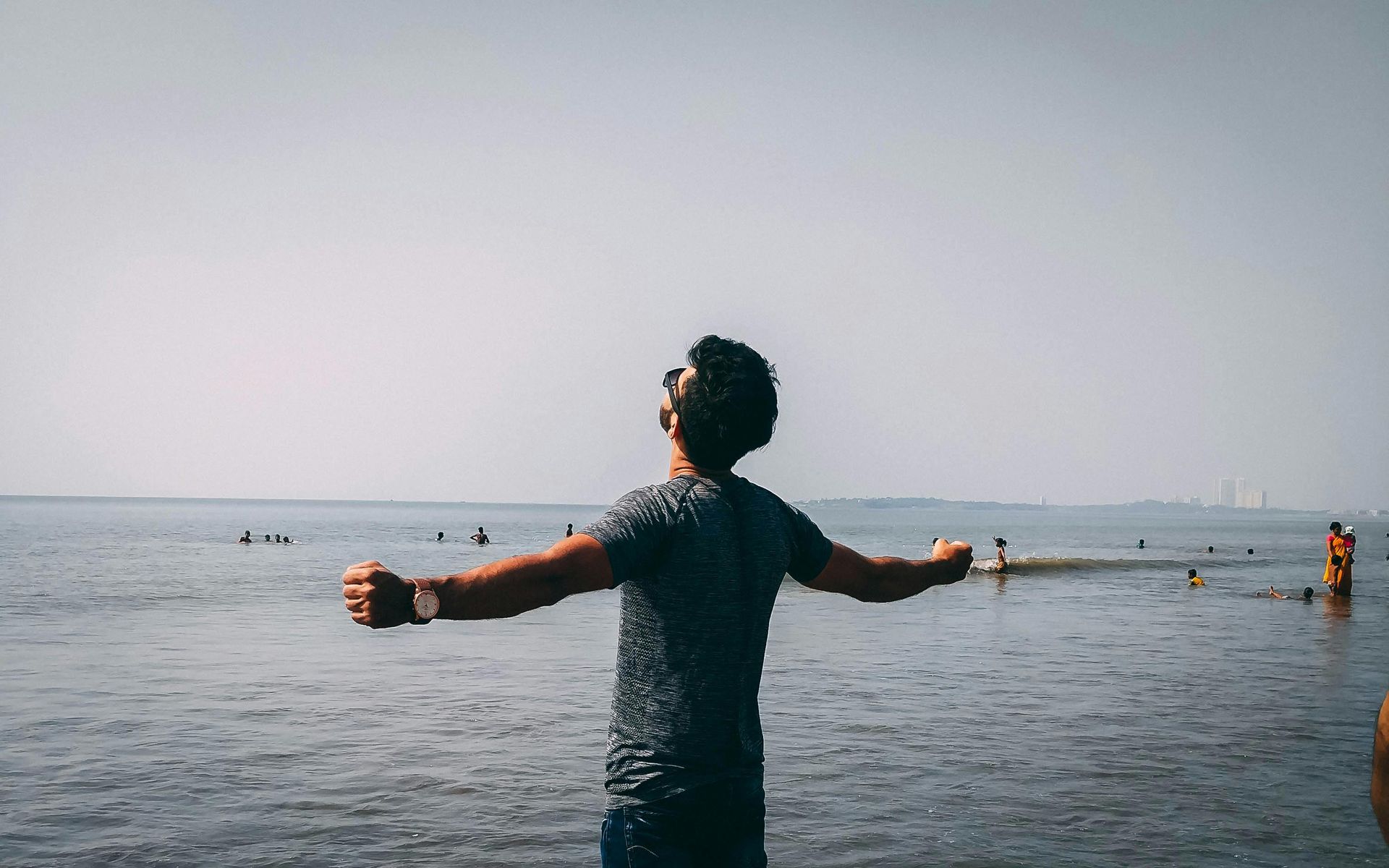 man with arms outstretched, standing by water