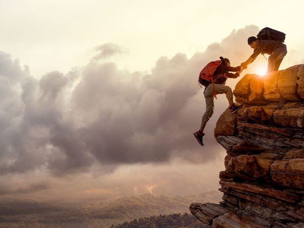 person helping another up on a rocky ledge