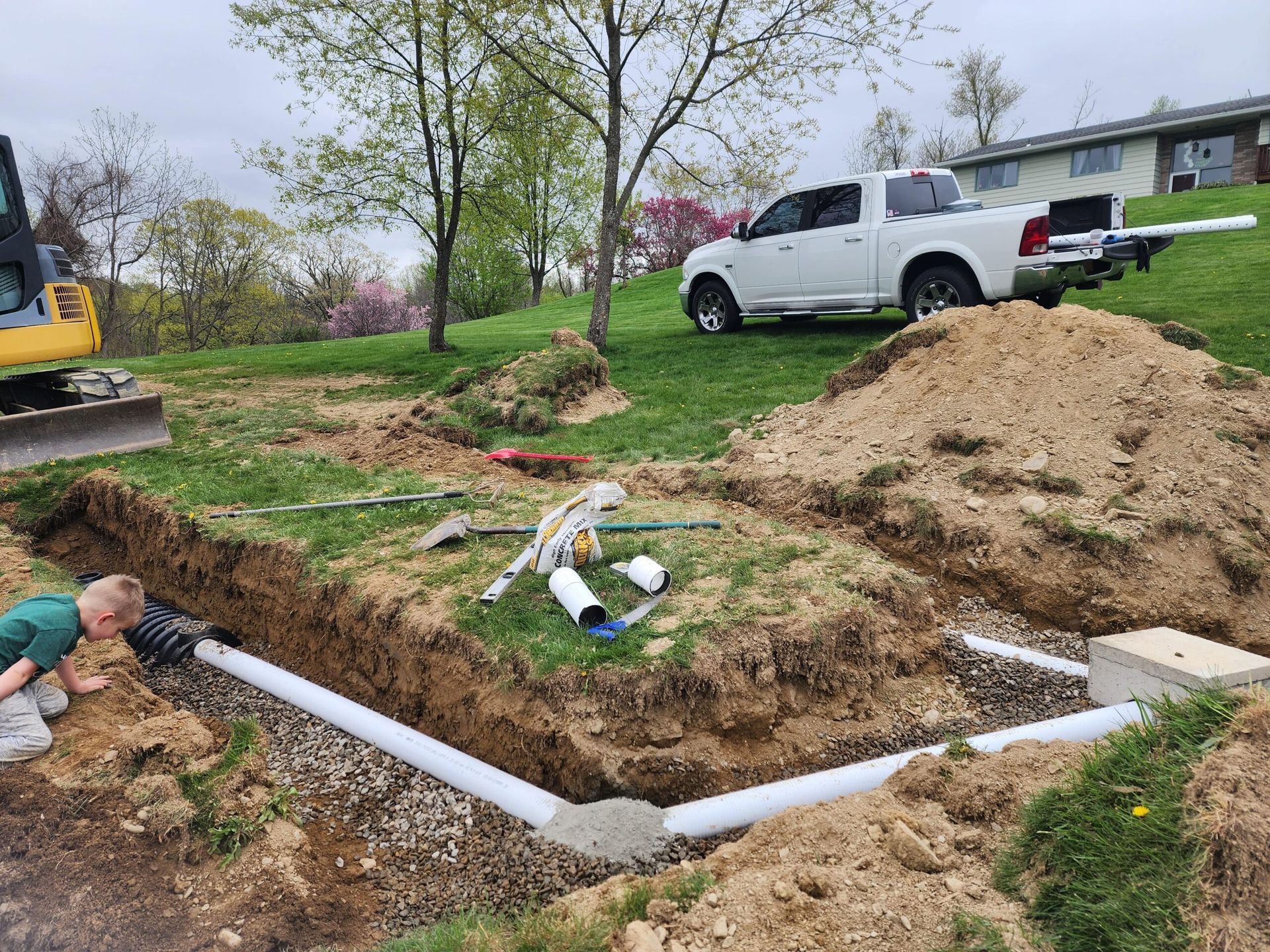A boy is digging in the dirt next to a truck.