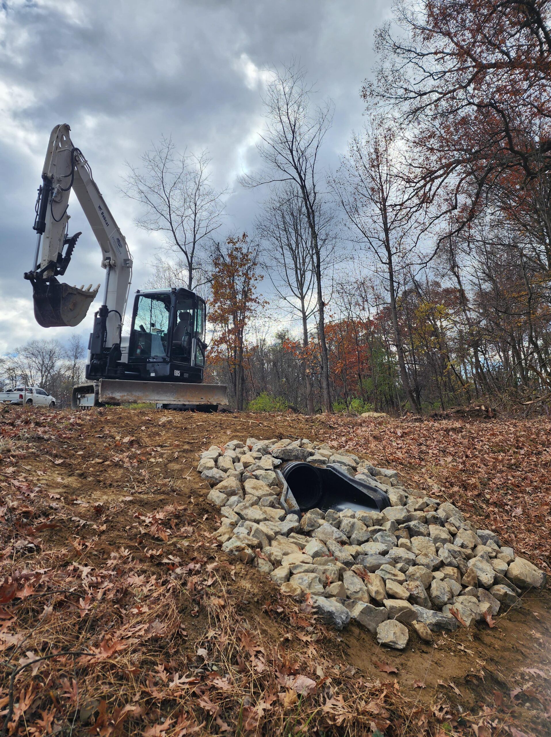 An excavator is digging a hole in the ground in a field.