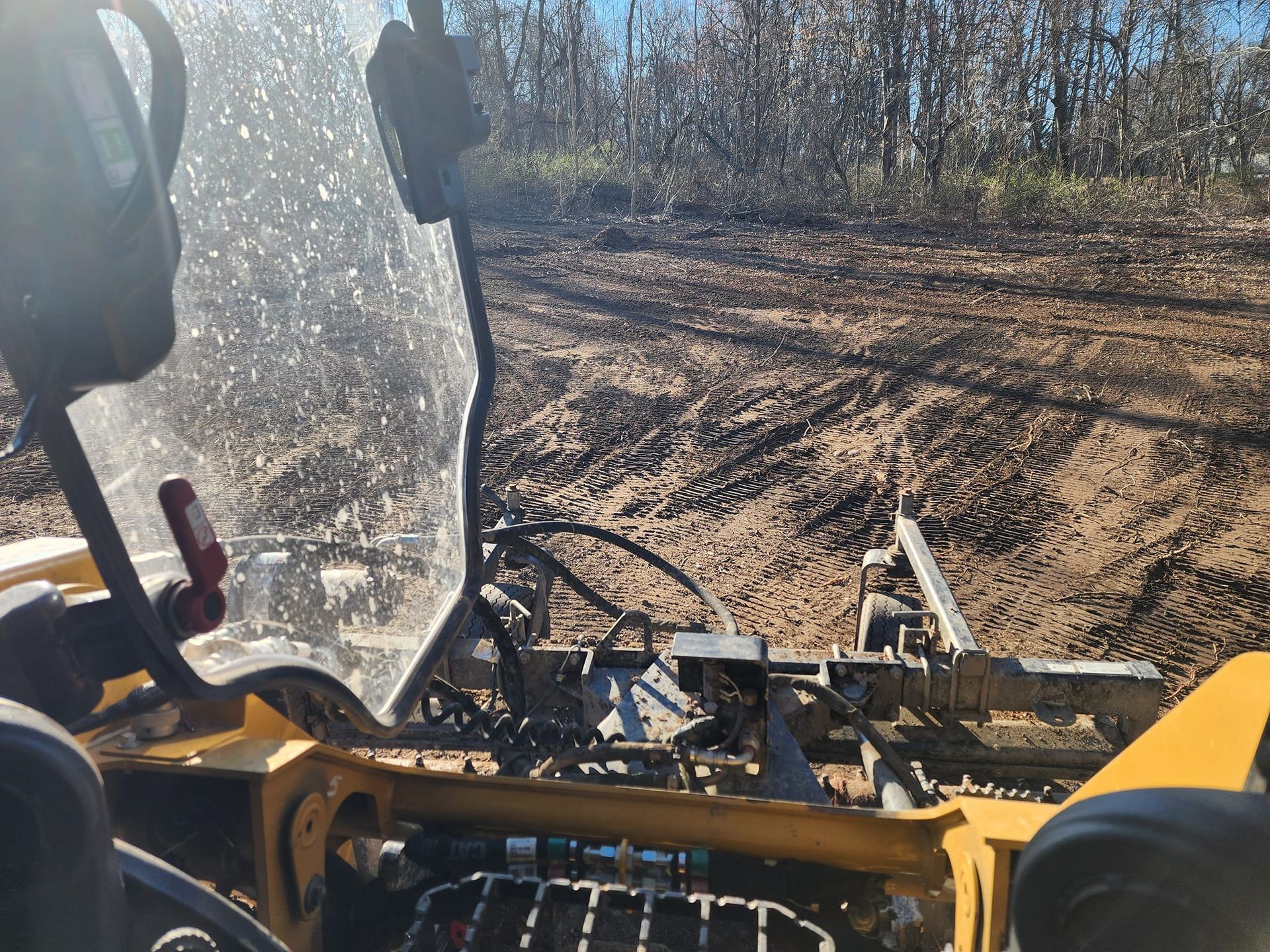 A person is driving a yellow vehicle on a dirt road.