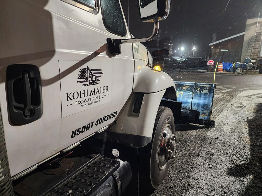 A white truck is parked in a parking lot at night.