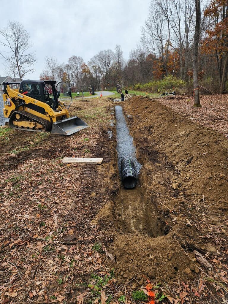 A bulldozer is digging a trench in the dirt next to a road.