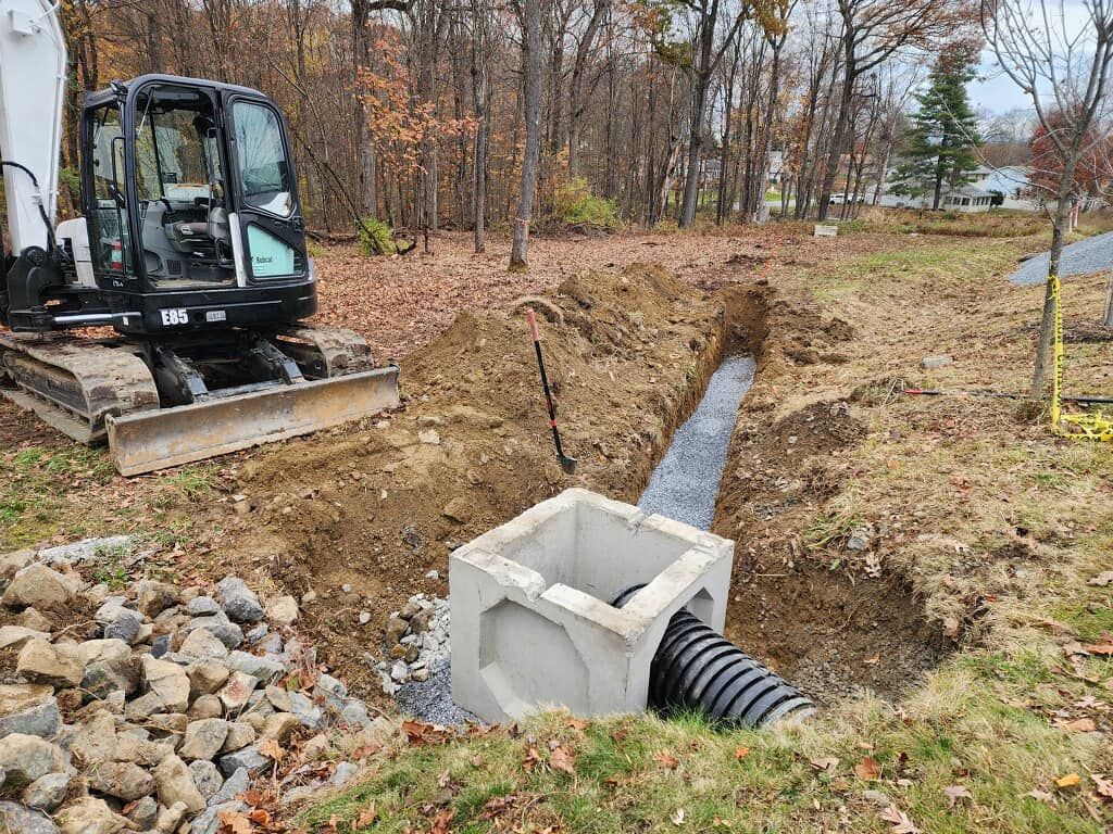 A bulldozer is digging a hole in the ground next to a pipe.