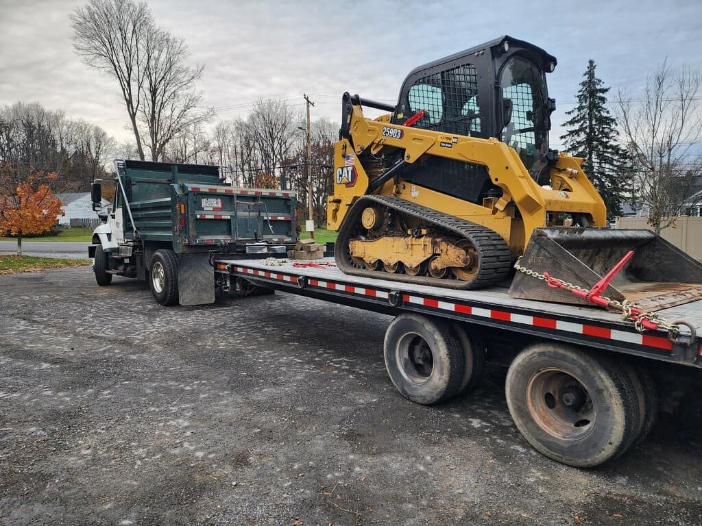 A bulldozer is being towed by a flatbed truck.