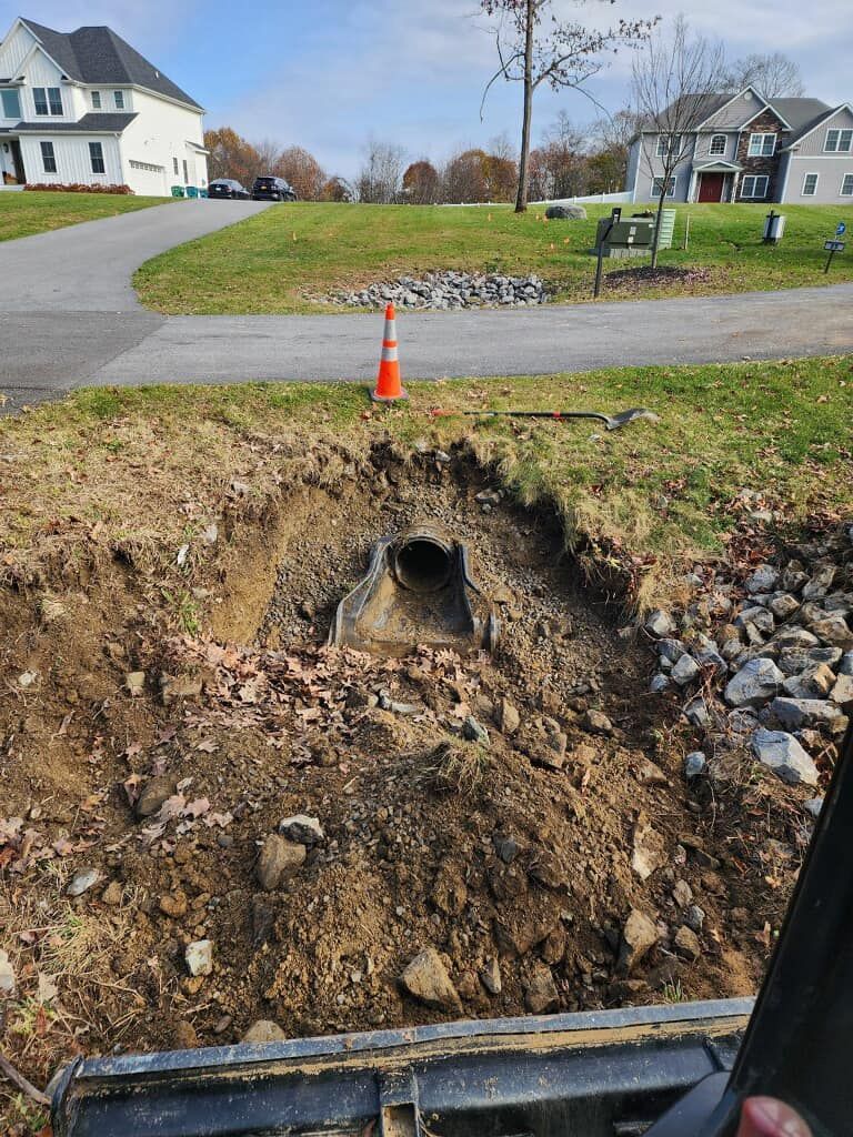 A person is digging a hole in the ground next to a road.